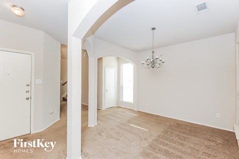 a spacious living room and dining room with white walls and a beige carpet
