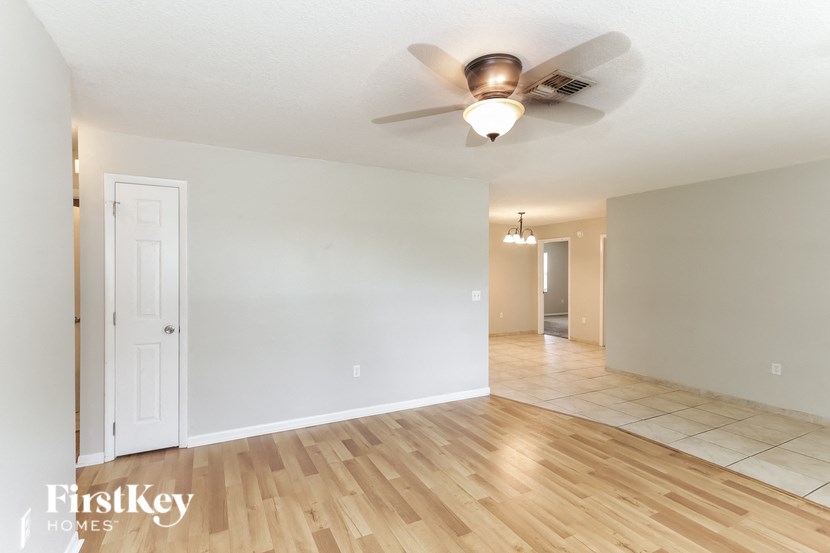 the living room and dining room with wood flooring and a ceiling fan