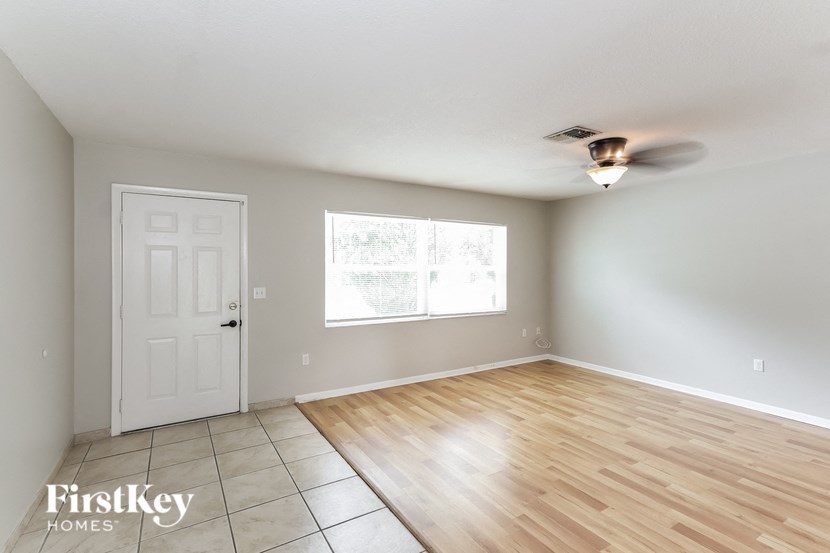 an empty living room with wood floors and a ceiling fan