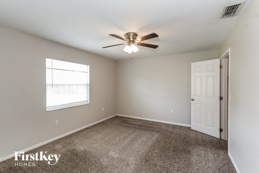 an empty room with a ceiling fan and a window