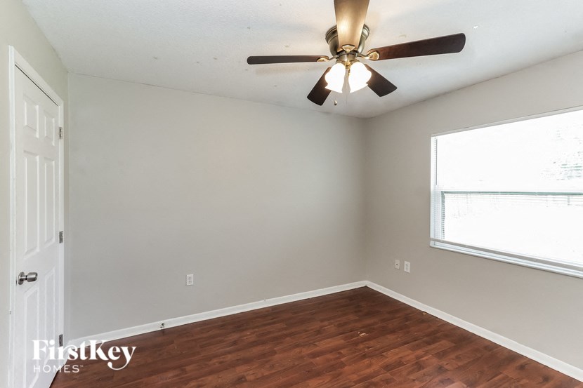 a bedroom with wood flooring and a ceiling fan