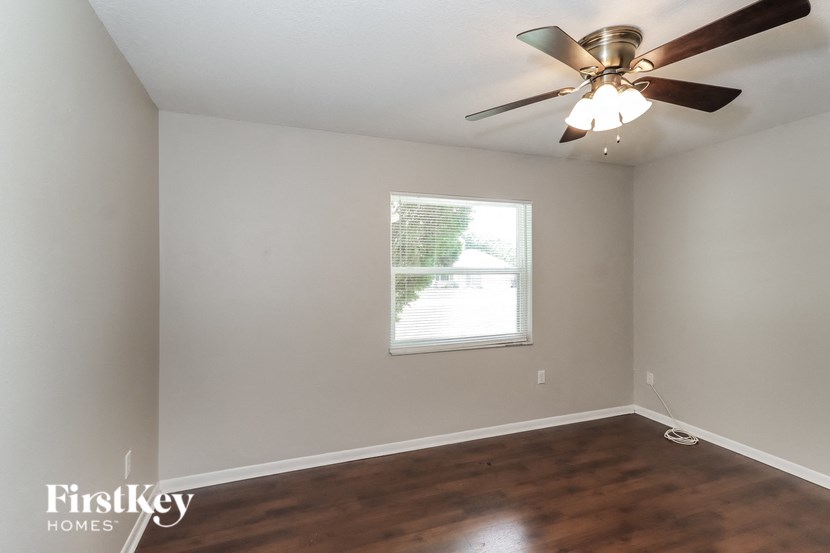 an empty room with a ceiling fan and a window