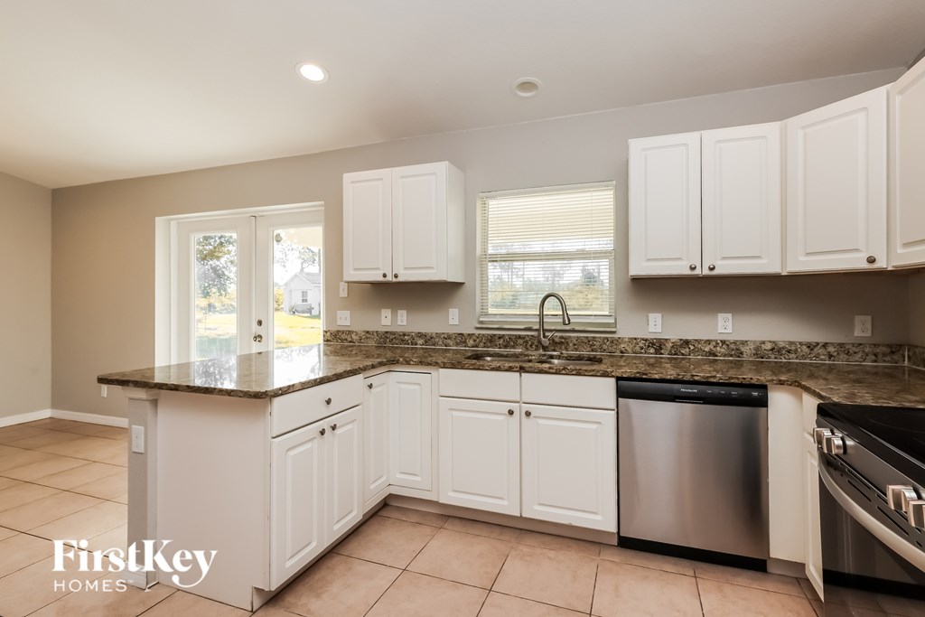 A kitchen with white cabinets and a granite countertop.