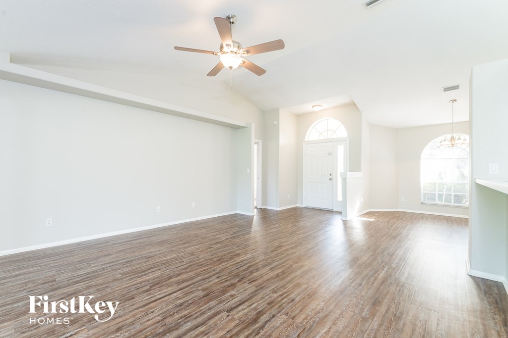 A spacious room with wooden floors and a ceiling fan.