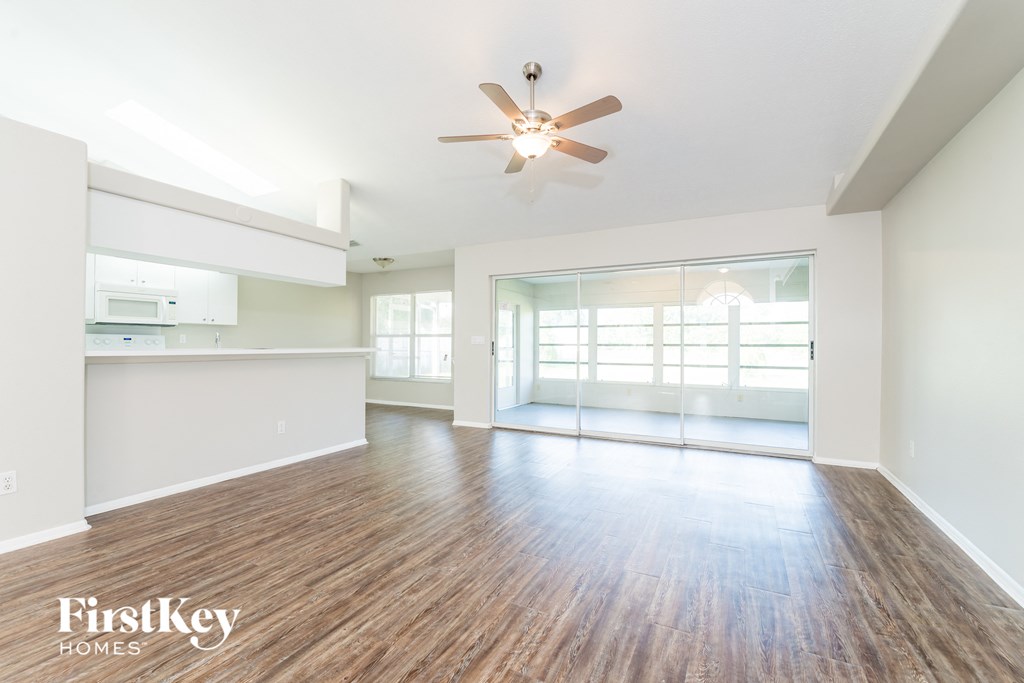 A spacious room with wooden floors and a ceiling fan.