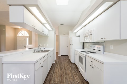 A kitchen with white cabinets and a wooden floor.