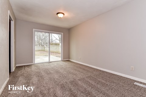 the living room of a home with carpet and a door to the backyard