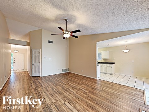 an empty living room with wood flooring and a ceiling fan