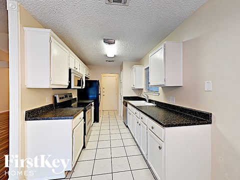 a white kitchen with white cabinets and black counter tops