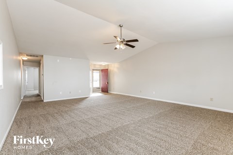 A spacious room with a carpeted floor and a ceiling fan.