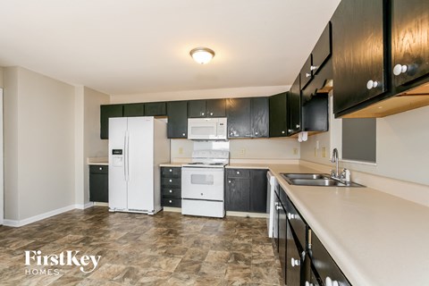 A kitchen with black cabinets and white appliances.