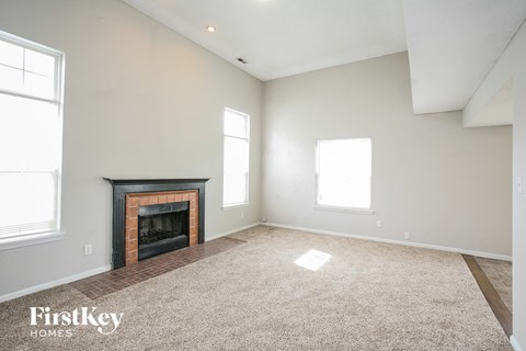 A spacious living room with a fireplace and two windows.