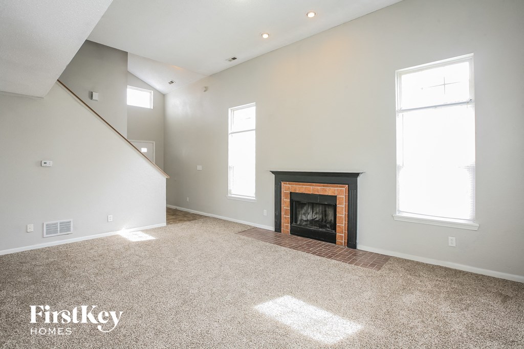 A spacious living room with a fireplace and a staircase.