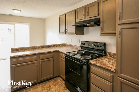 A kitchen with a black stove top oven and brown cabinets.