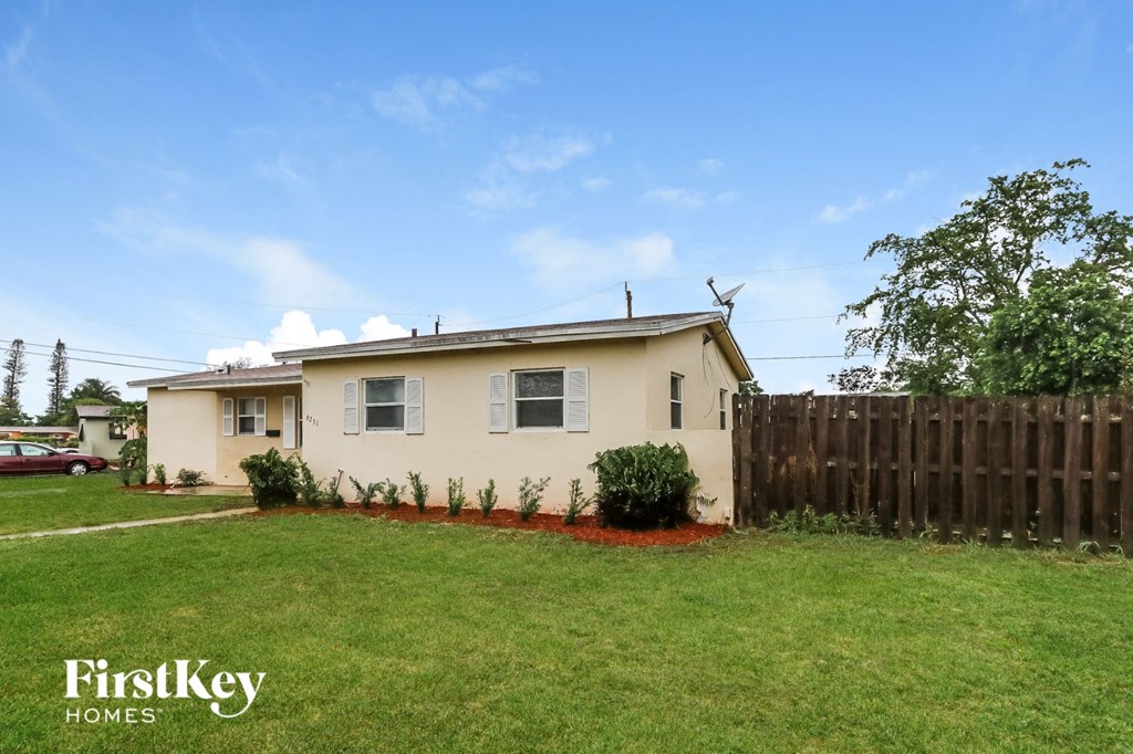 a small house with a yard and a wooden fence