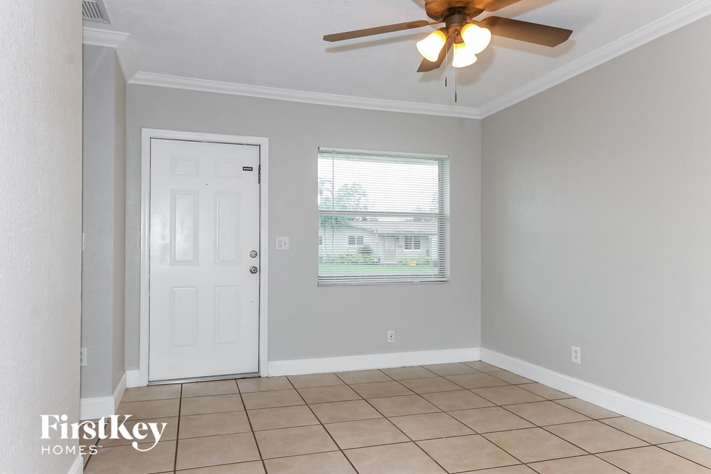 an empty living room with a ceiling fan and a white door