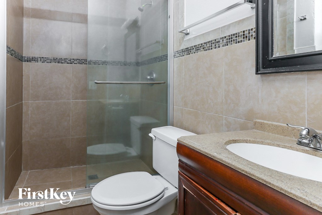 a bathroom with a shower toilet and sink and a mirror