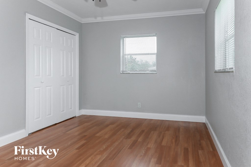 the second bedroom with hardwood flooring and a window