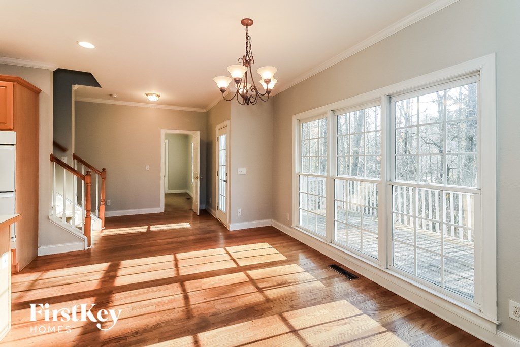 an empty living room with large windows and a wooden floor