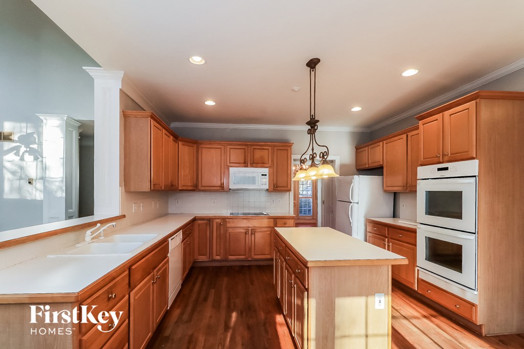 a kitchen with wooden cabinets and white appliances and a white counter top