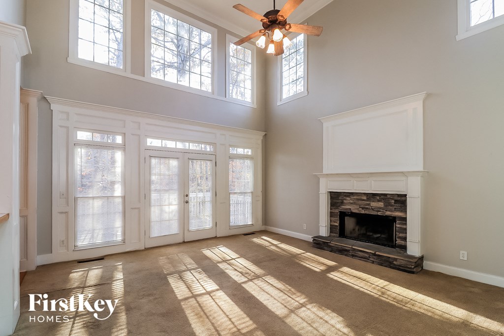 an empty living room with a ceiling fan and a fireplace