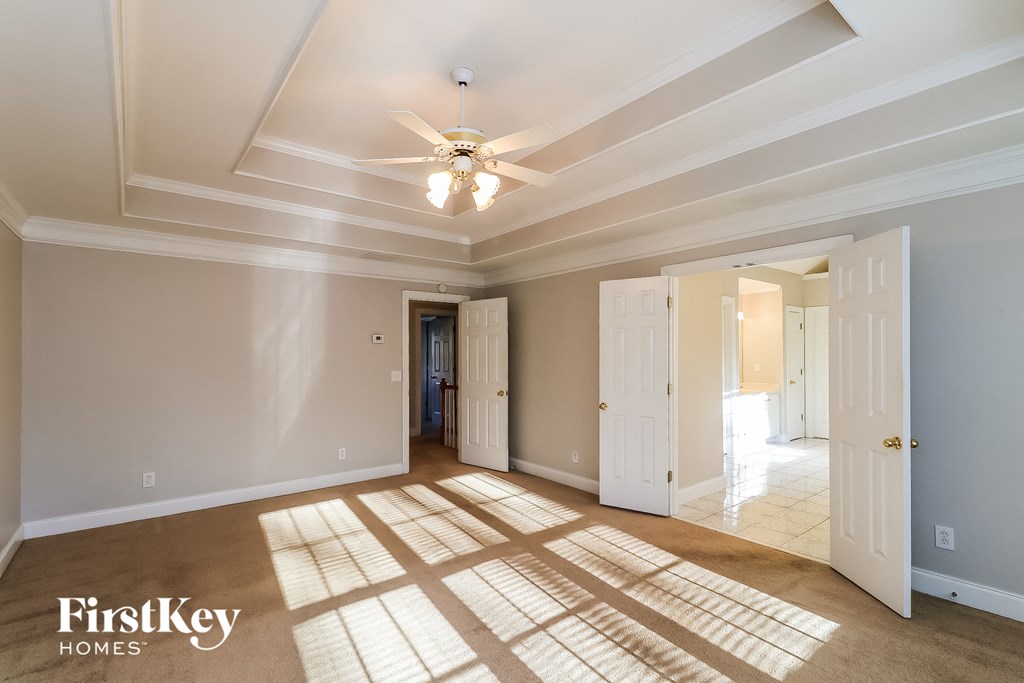 a living room with a ceiling fan and a door to a hallway