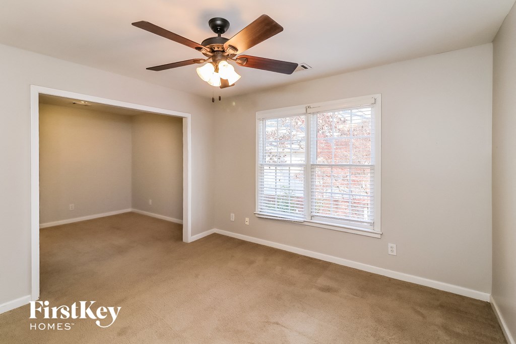 an empty living room with a ceiling fan and a window