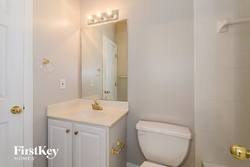 a white bathroom with a toilet and a sink and a mirror