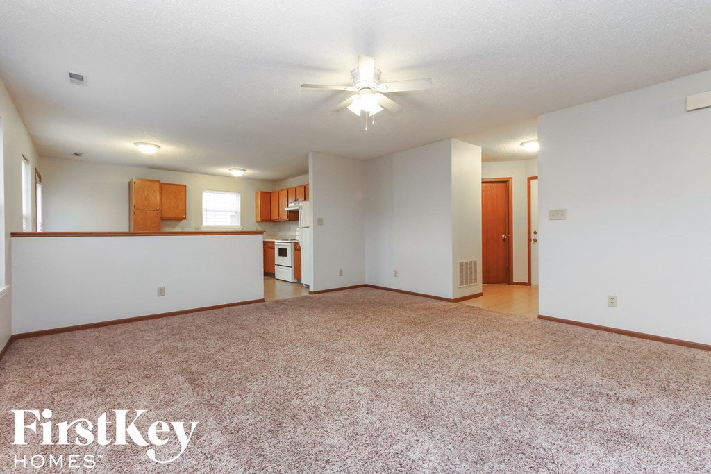 A spacious room with a carpeted floor and a ceiling fan.