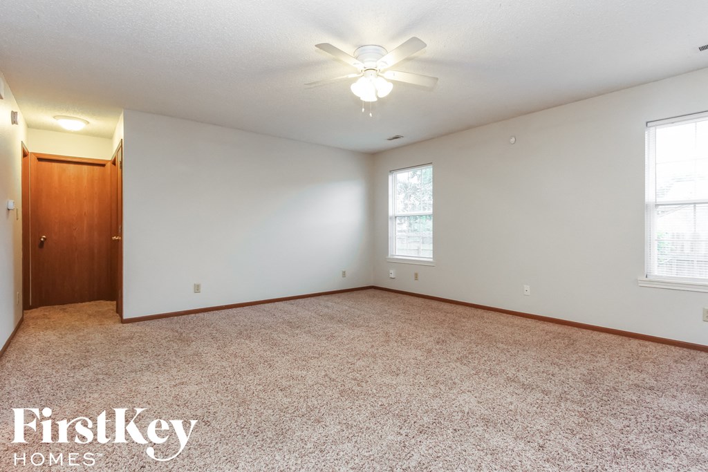 A room with a carpeted floor and a ceiling fan.
