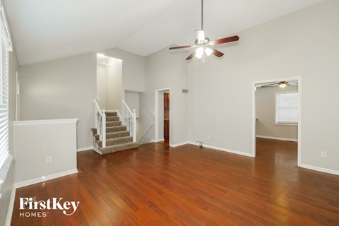 A spacious room with wooden floors and a ceiling fan.