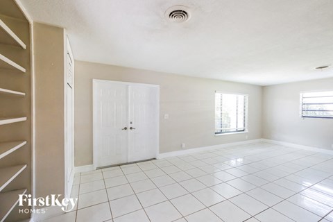 an empty living room with a white tile floor and a closet