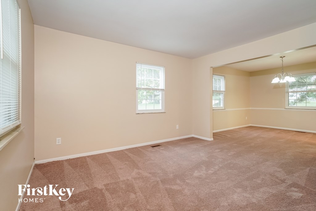 a spacious living room with carpeting and two windows