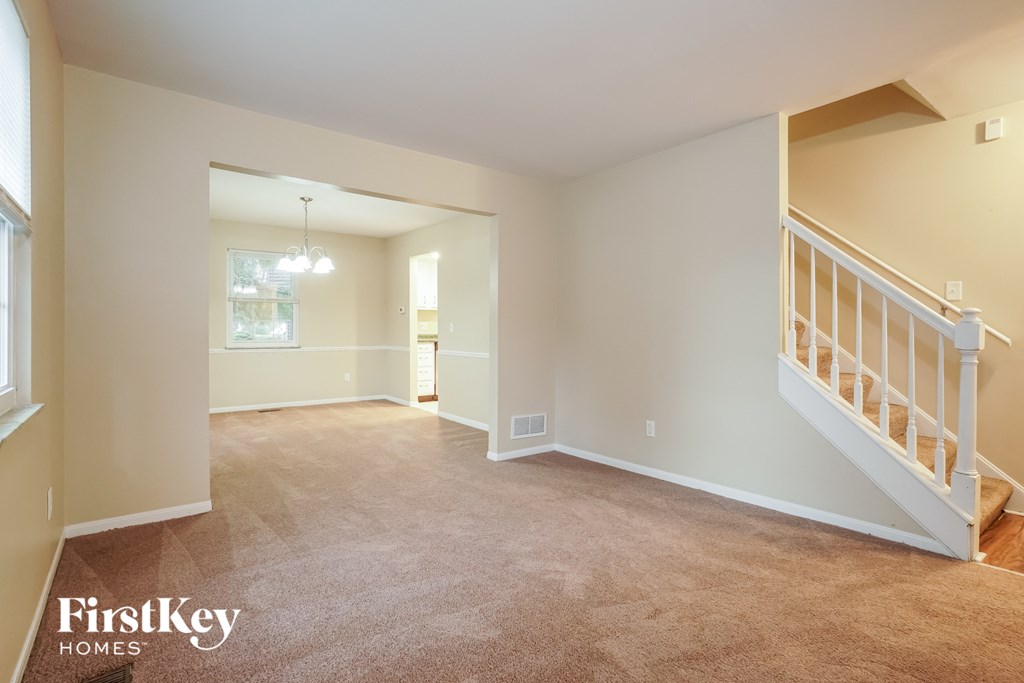 a living room with a staircase and a carpeted floor