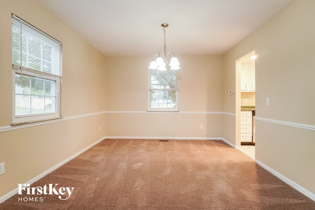 an empty dining room with a chandelier and windows