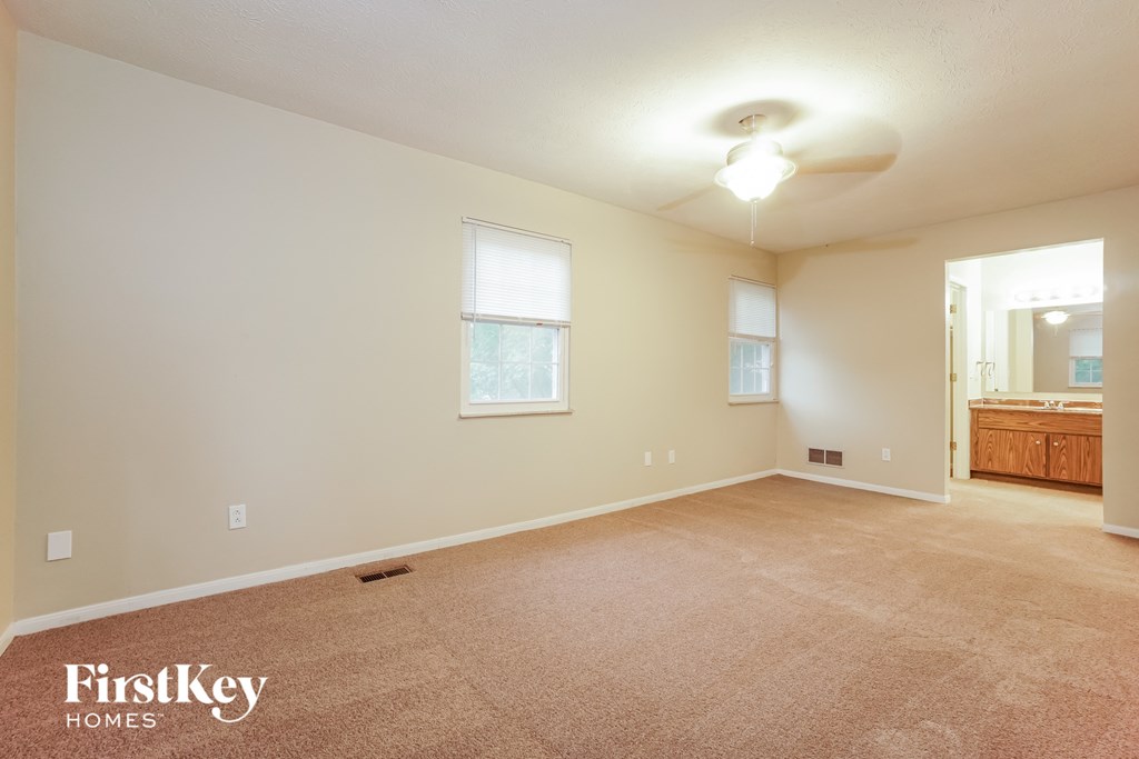 the spacious living room with carpeted flooring and white walls