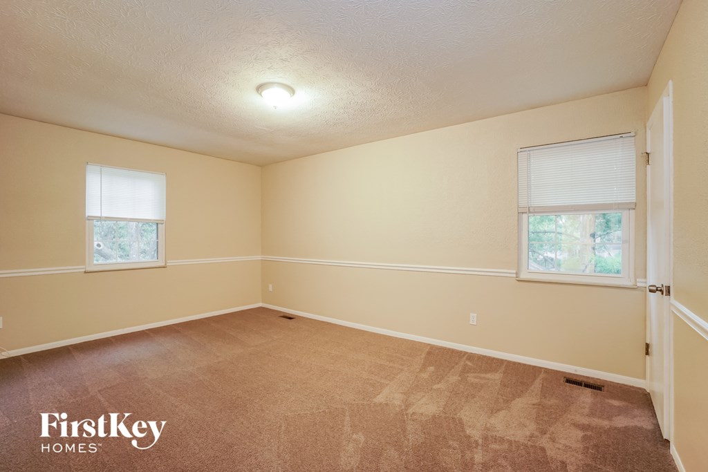 a bedroom with a carpeted floor and two windows