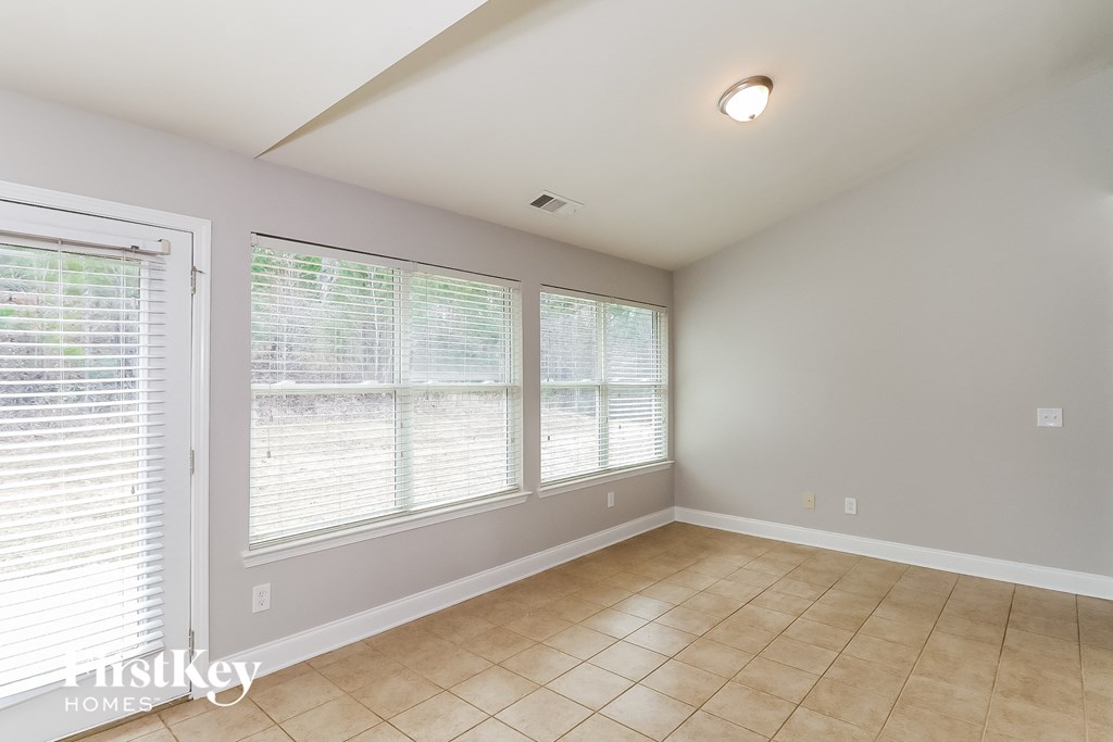 an empty living room with large windows and a tiled floor