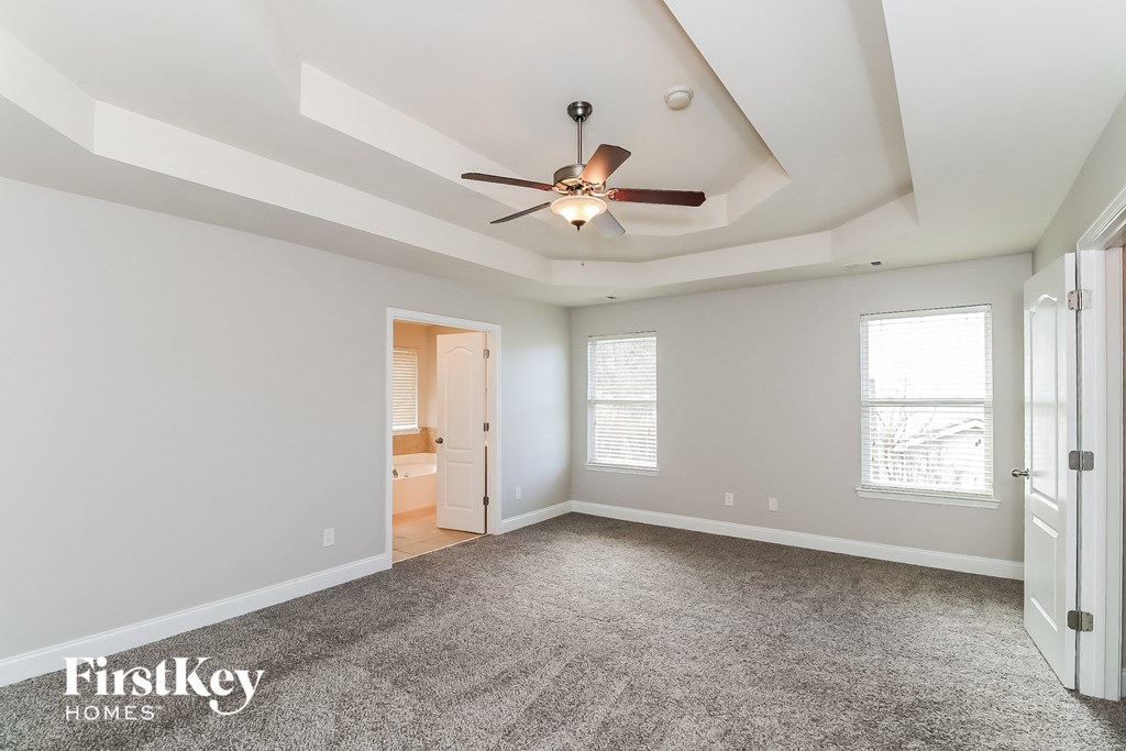 an empty room with a ceiling fan and a door to a bathroom
