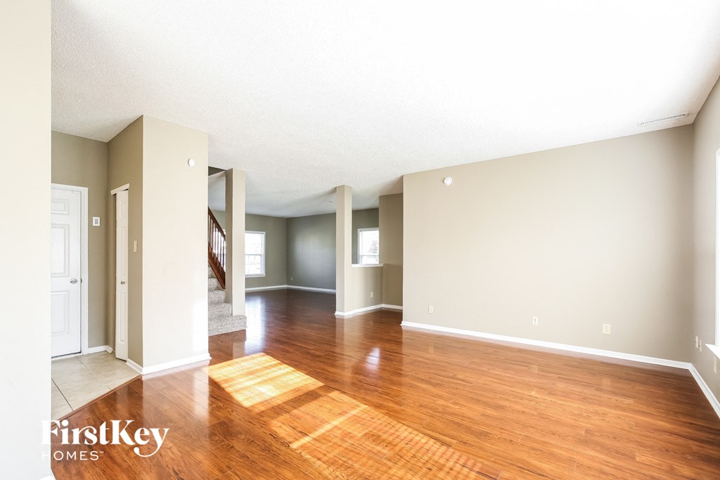 the living room and dining room of an empty house with wood flooring