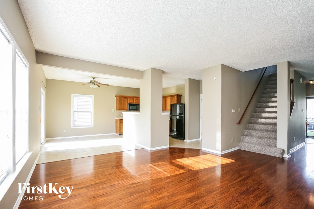 a living room with a staircase and a hard wood floor