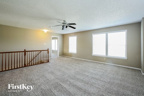 a living room with carpet and a ceiling fan