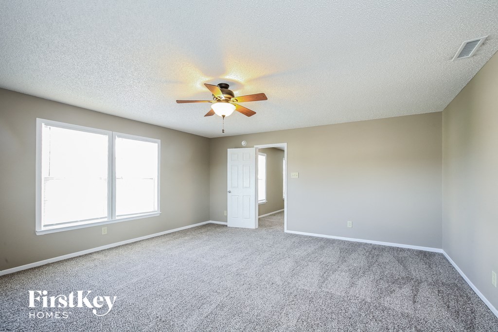 the spacious living room with ceiling fan and carpeting