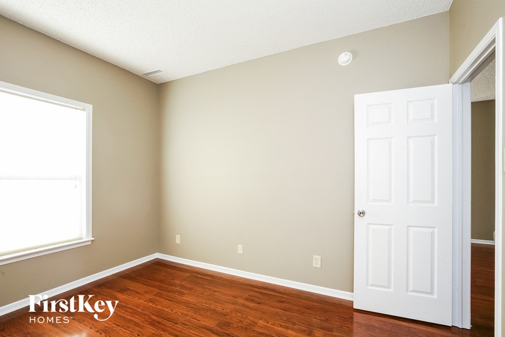 a bedroom with wood floors and a white door
