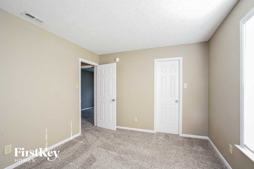 a living room with two doors and a carpeted floor