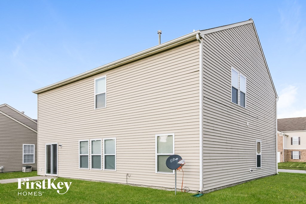a white house with tan siding on a green lawn