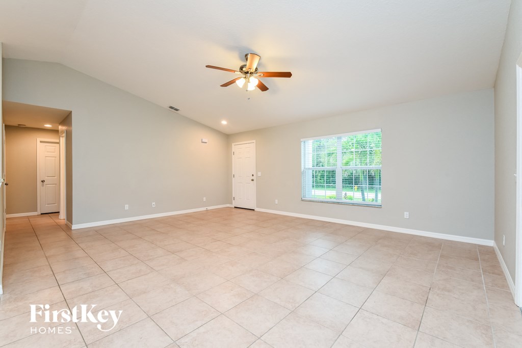 A spacious room with a ceiling fan and a large window.