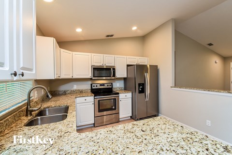 A kitchen with white cabinets and a granite countertop.