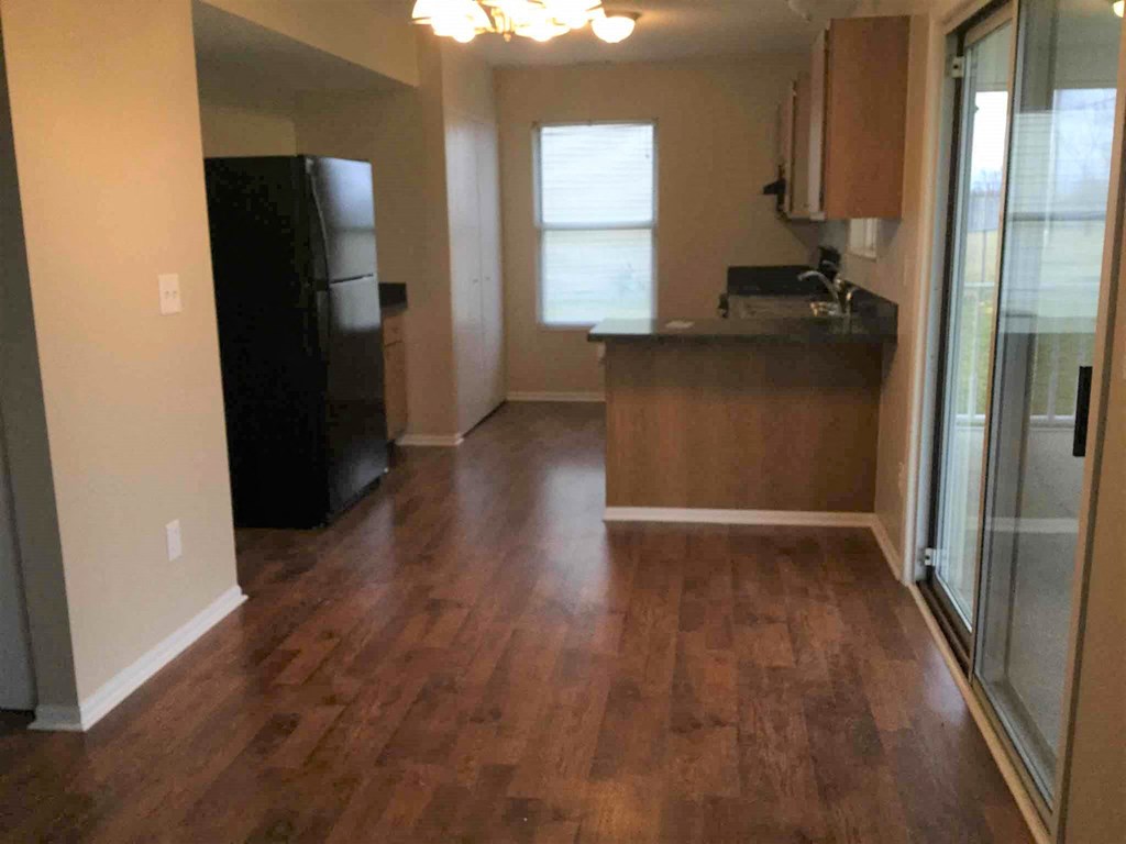 an empty kitchen and living room with a hard wood floor