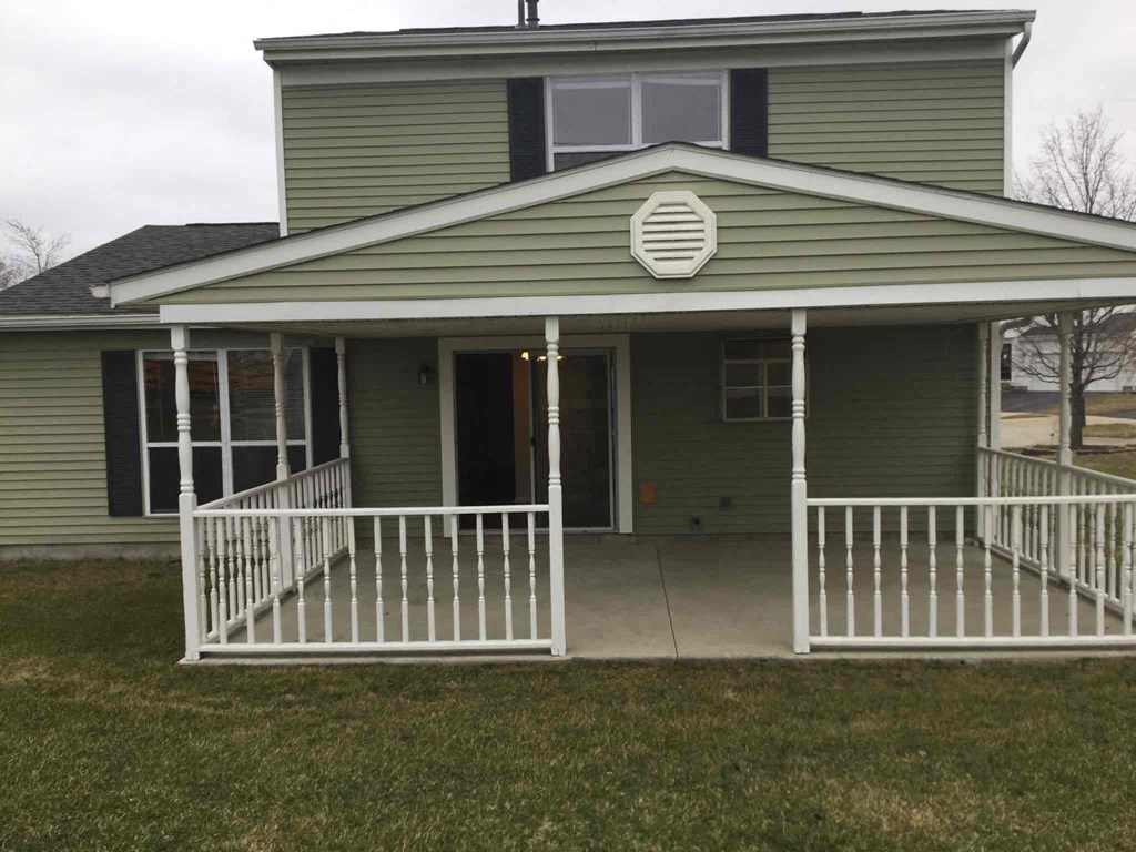 a green house with a porch and a white fence